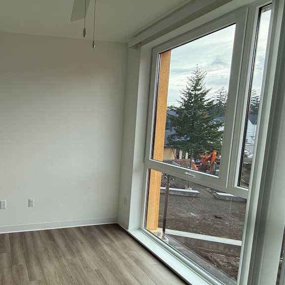 a room with a large window and wooden flooring.