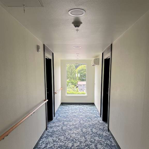 an empty hallway with white walls and blue carpet