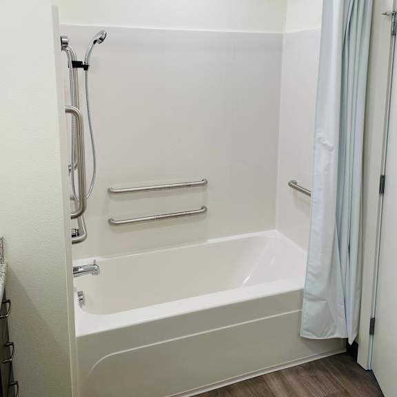a small white bathtub with a shower curtain in a 555 waverly unit