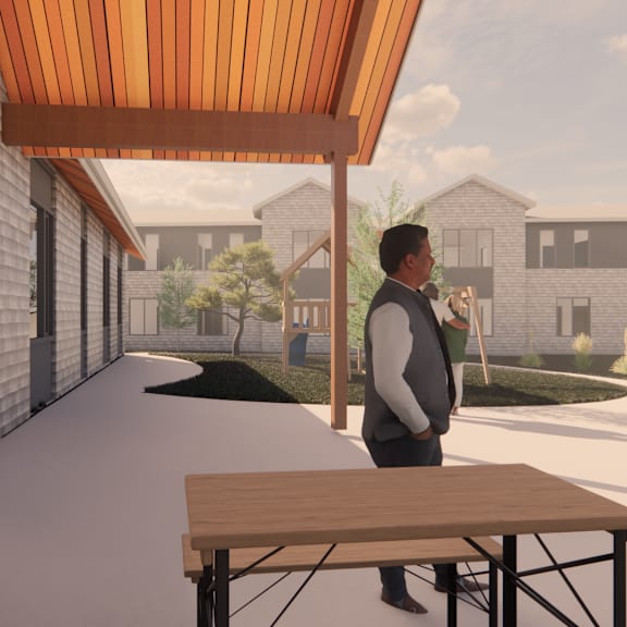 a man stands on a patio with a table and chairs.