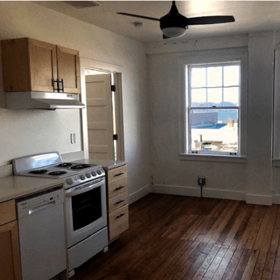 a kitchen with a stove top oven and a window overlooking a body of water.