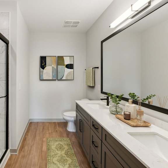 Thumbnail 12 of 21 A bathroom with a marble shower and a wooden floor.