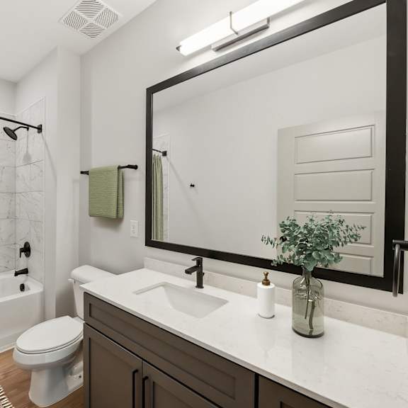Thumbnail 15 of 21 A bathroom with a white toilet, a white sink, and a green shower curtain.