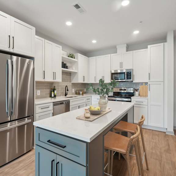 Thumbnail 3 of 21 A modern kitchen with a stainless steel refrigerator and a marble countertop.