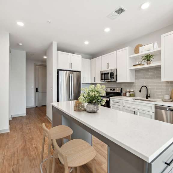 Thumbnail 2 of 10 A kitchen with white cabinets and a white countertop.