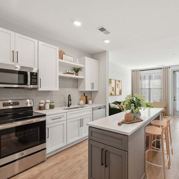Thumbnail 3 of 10 A modern kitchen with white cabinets and stainless steel appliances.