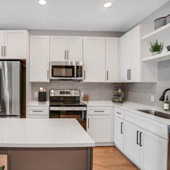 Thumbnail 3 of 12 a white kitchen with stainless steel appliances and white cabinets