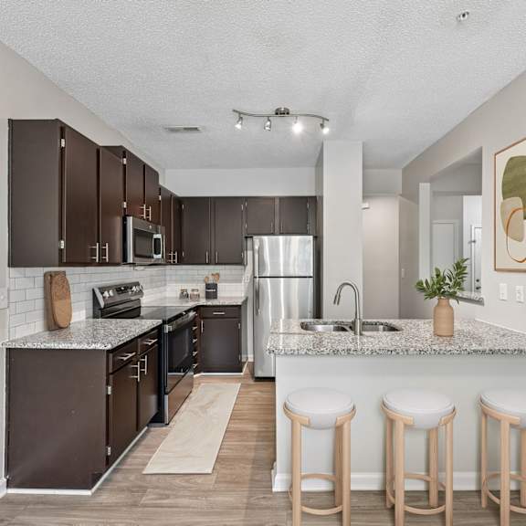 Thumbnail 4 of 17 A kitchen with brown cabinets and a granite countertop.