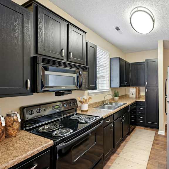 Thumbnail 2 of 8 A kitchen with black cabinets and a black stove top oven.