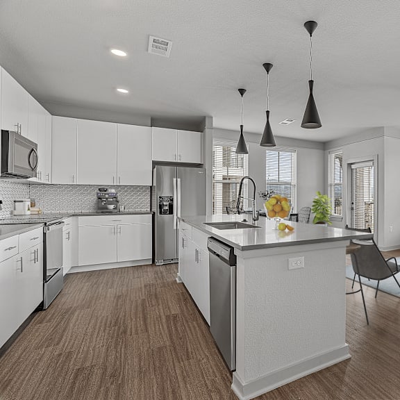 A modern kitchen with white cabinets and a wooden floor.