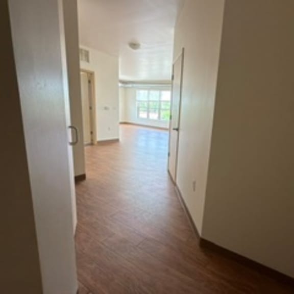 a long hallway with wood floors and white walls.