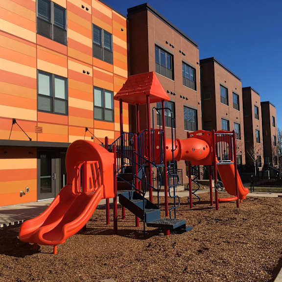 a playground with a red slide in front of a building.