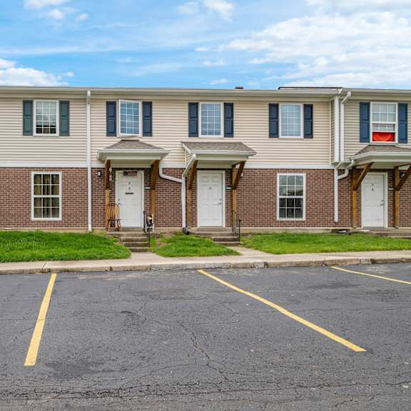 a row of townhouses with a parking lot in front.