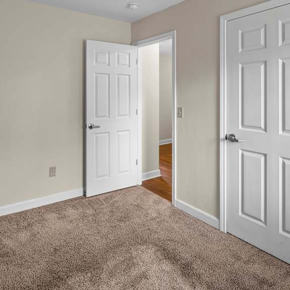a room with a carpeted floor and two white doors.