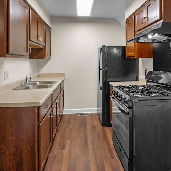 a kitchen with a black stove top oven and wooden cabinets.