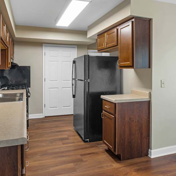 a kitchen with a black fridge and wooden cabinets.