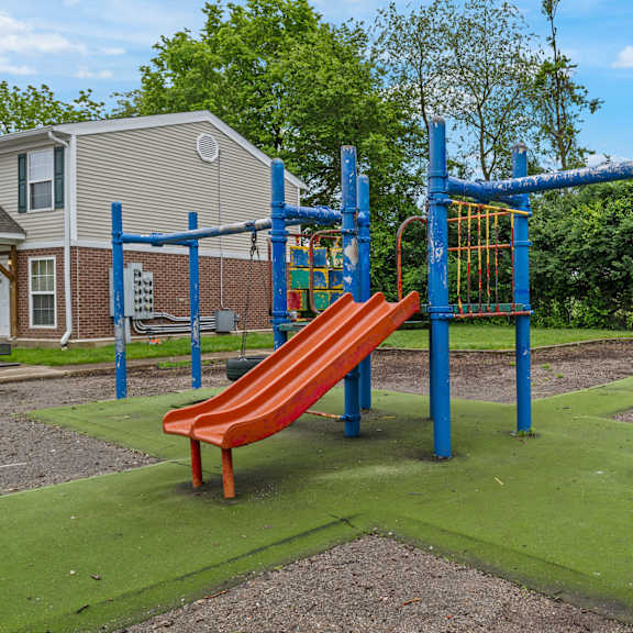 a playground with a red slide and a blue monkey bar.