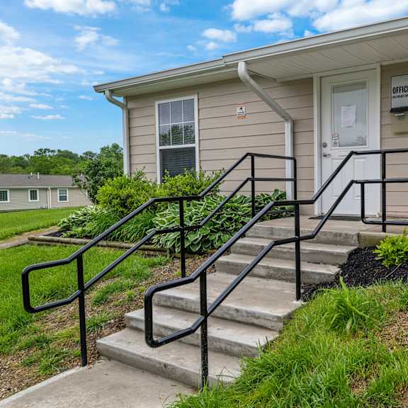 a beige house with a black railing on the stairs.
