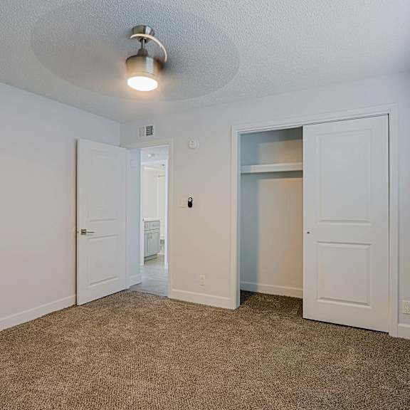 A room with a carpeted floor and a ceiling fan.