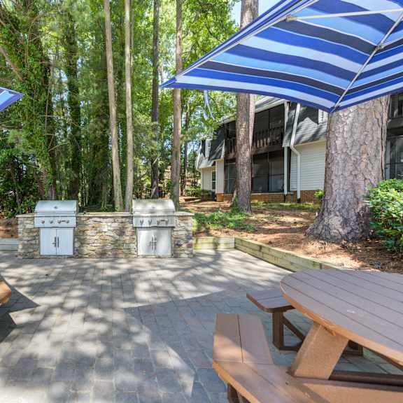 a patio with a table and benches under blue striped umbrellas.
