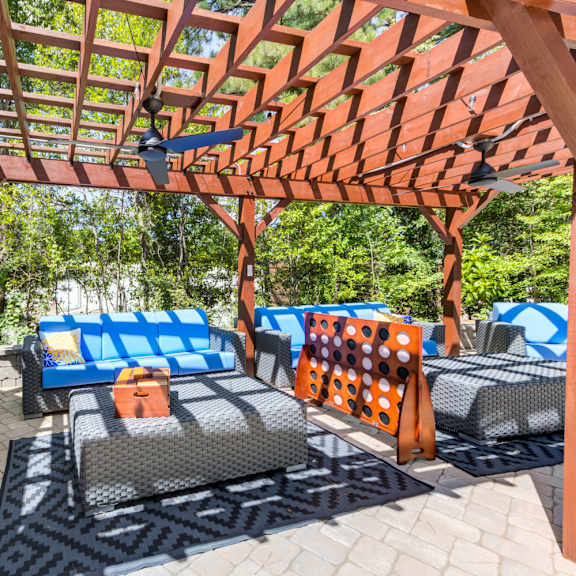 a patio with a wooden pergola and blue cushioned furniture.