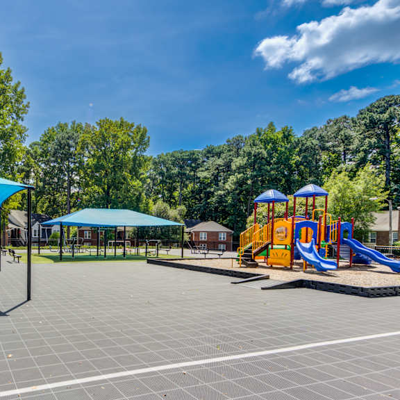 a playground with a slide, picnic tables, and umbrellas.