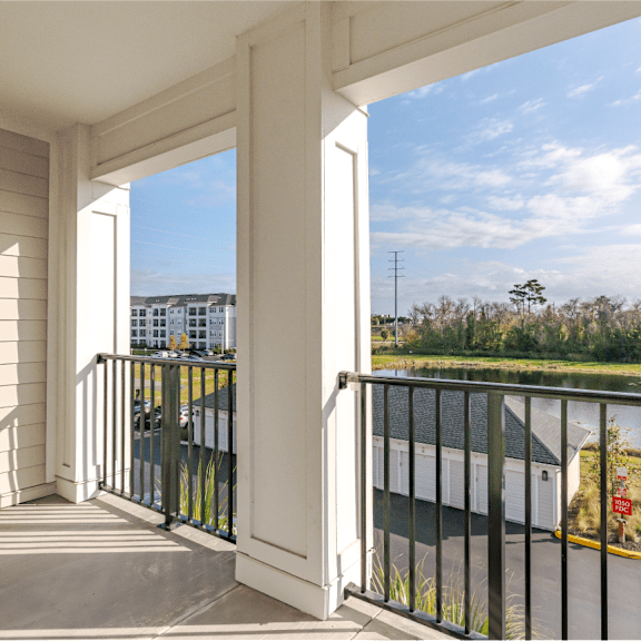 a balcony with a view of a parking lot and trees.