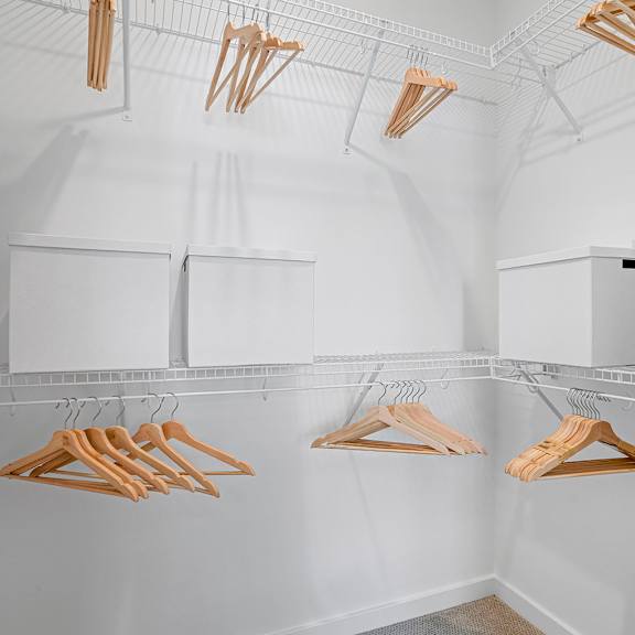 a walk in closet with wooden clothes drying racks at madison waterford lakes, orlando, fl