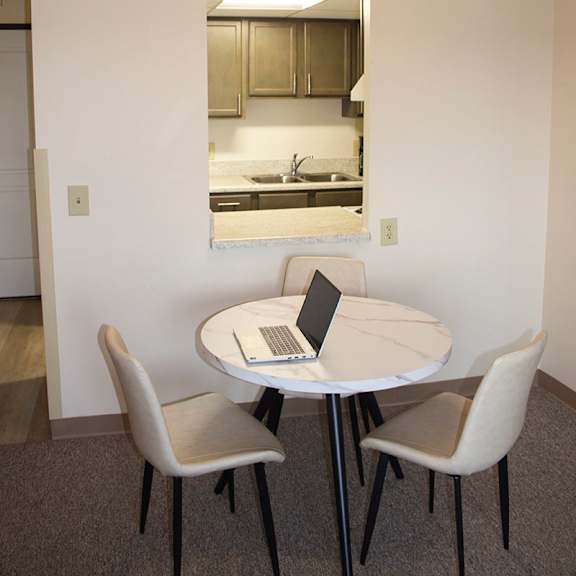 a round table with a laptop on it and two chairs.