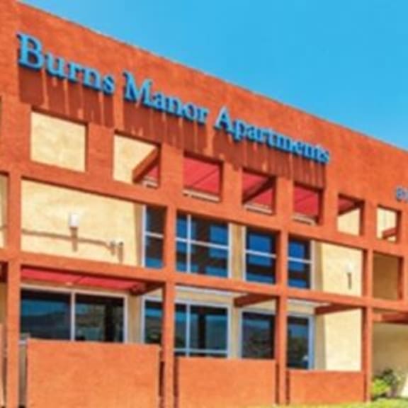 the burnt manor apartments building has a red facade with white trim.