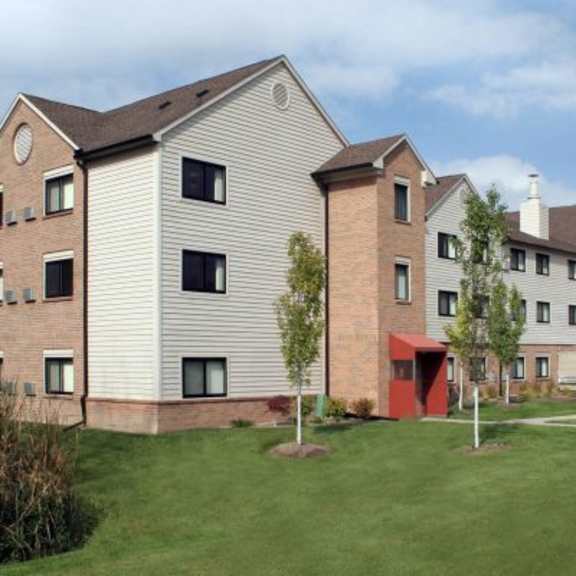 a large building with a red door and a green lawn in front.