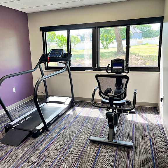 a treadmill and a stationary bike are in a room with purple walls.