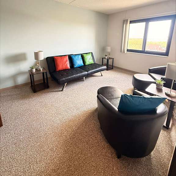 a living room with a black couch and a small table with a plant on it.
