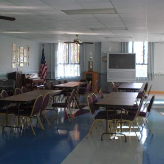 a classroom with tables and chairs and a flag hanging on the wall.