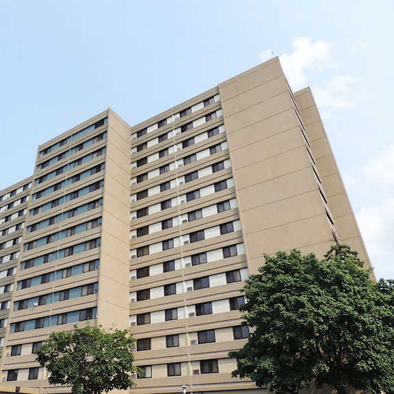 a tall building with many windows and trees in front.