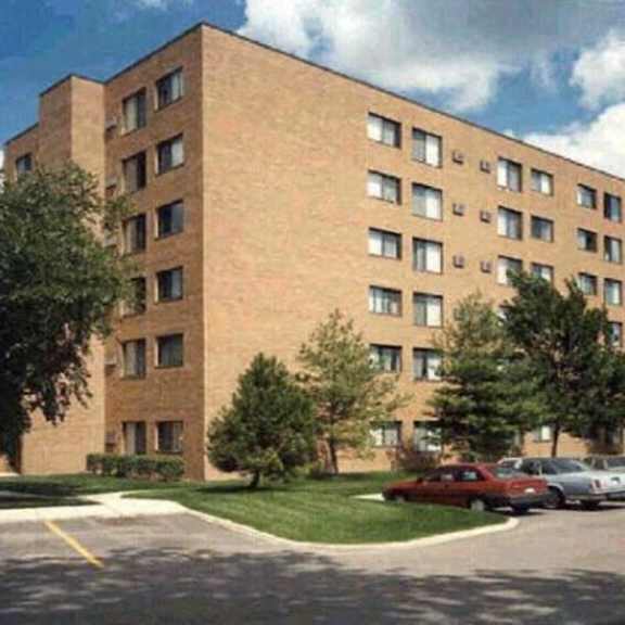 a large brick building with a parking lot in front.