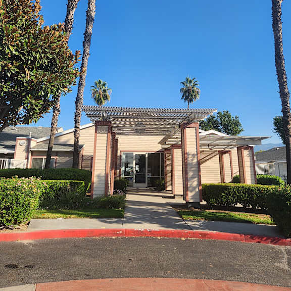 a building with a balcony is seen through the branches of palm trees.