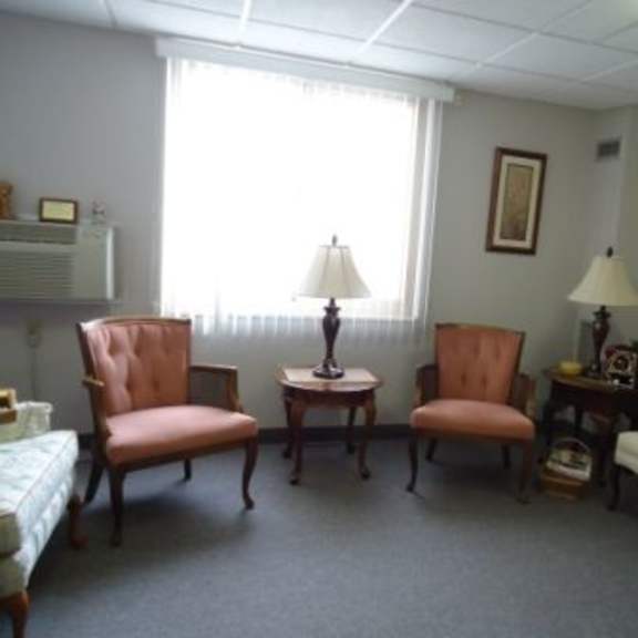 a living room with a sofa, two chairs, and a table with a lamp on it.