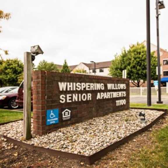 a sign for whispering willows senior apartments is displayed in front of a building.