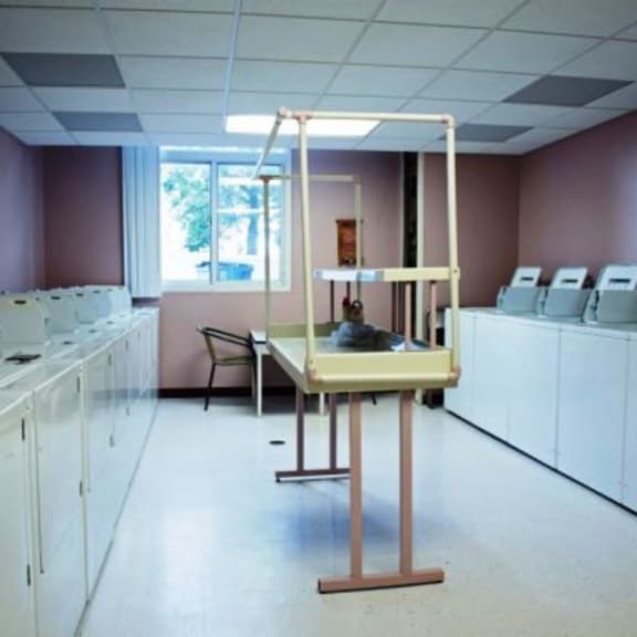 a laundromat with a washer and dryer in each cubicle.