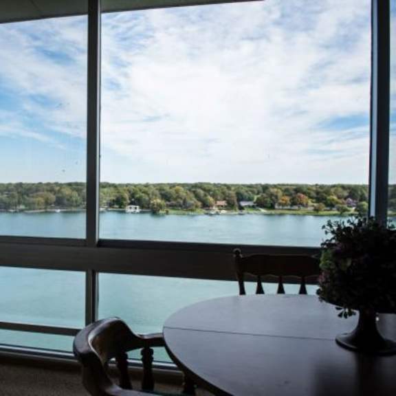 a table with a vase of flowers sits in front of a large window overlooking a body of water.