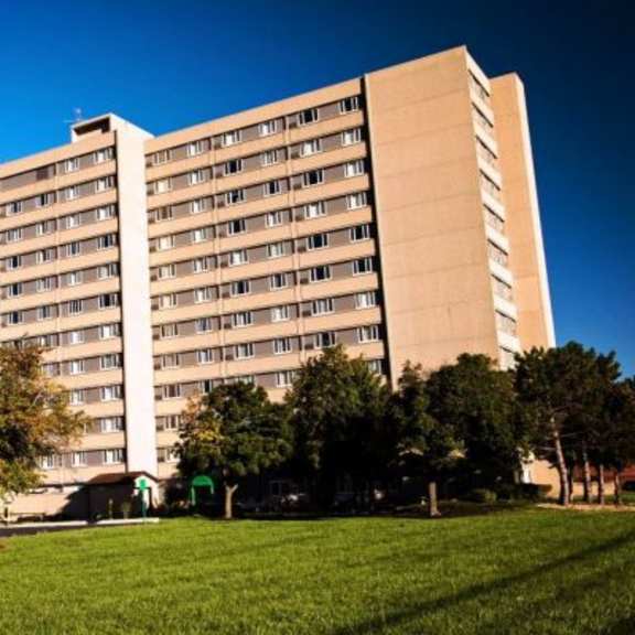a large beige building with a green lawn in front.