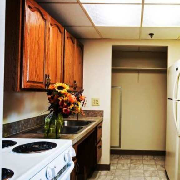 a kitchen with a white stove top oven, a white refrigerator, and wooden cabinets.