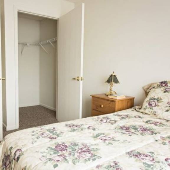 a bedroom with a floral bedspread and a lamp on a nightstand.