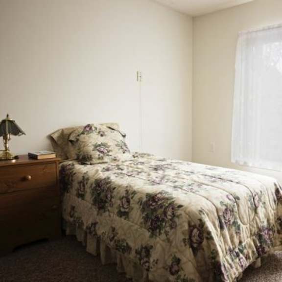 a bedroom with a floral bedspread and a window with curtains.