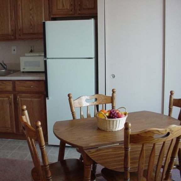a kitchen with a white fridge and wooden chairs.