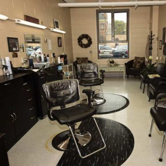 a black and white image of a salon with chairs and a mirror.