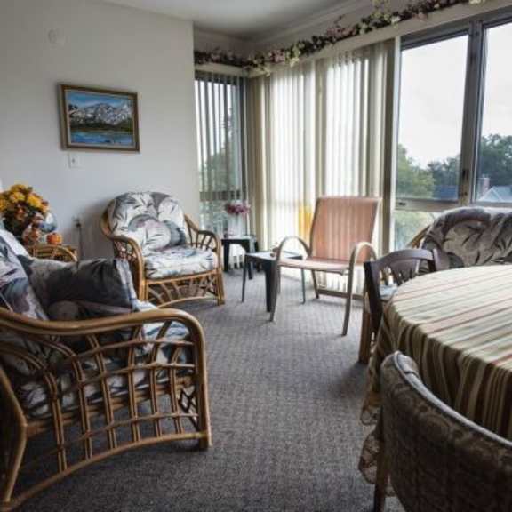 a living room with a sofa, chairs, and a table with a vase of flowers on it.