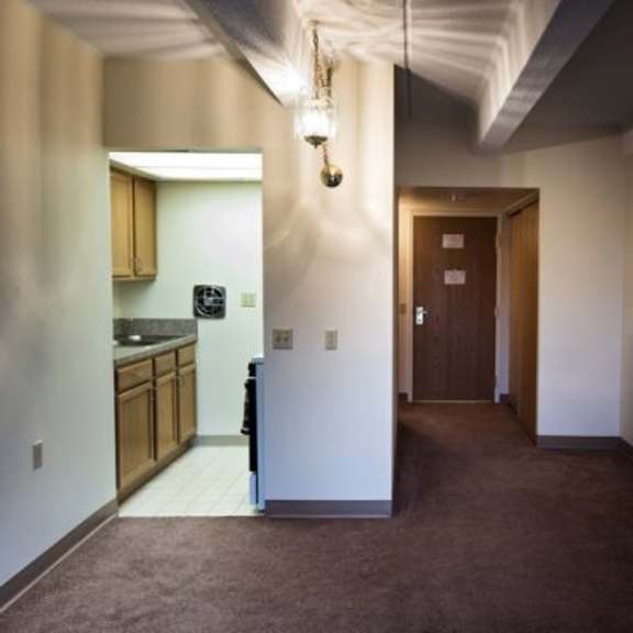 a hallway with a brown carpet and a door on the right.