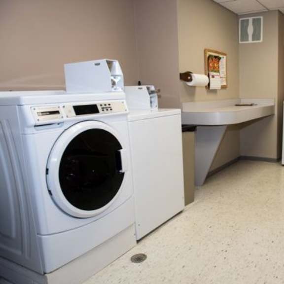 a laundry room with a washer and dryer, a sink, and a chair.